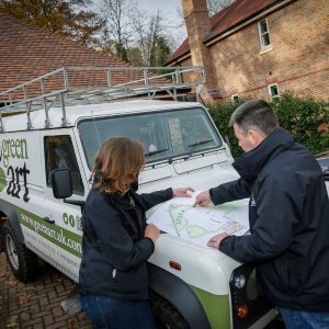 George and Jo reviewing a design on site, leaning on the GreenArt landrover