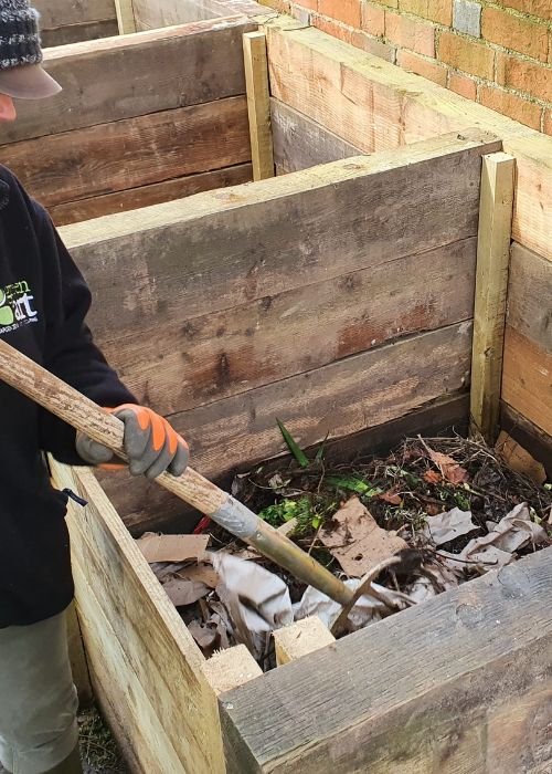 Image of greenart gardener carrying out winter gardening job of turning compost